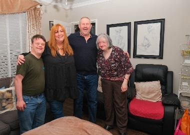 A picture of people stood together smiling at home