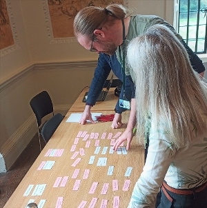 An photo of three people looking at coloured cards on a table at Shaw House.