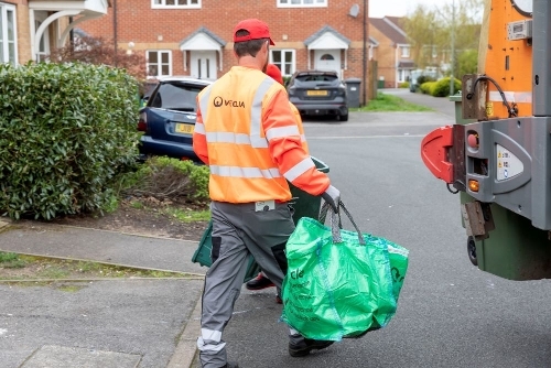 2025-recycling man carrying green bag and box to recycling van