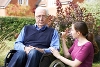 A young woman supporting elderly man in a wheelchair.